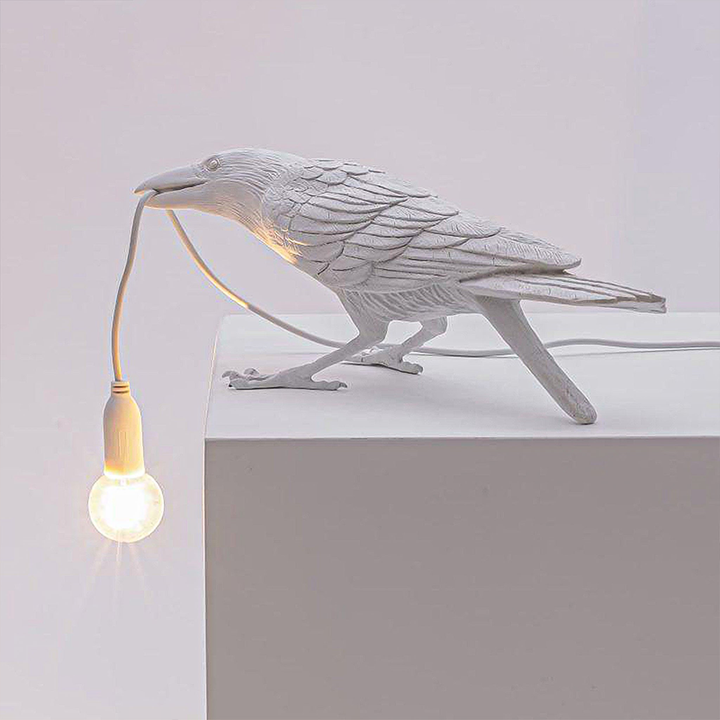 A photo of the Raven Lamp on a bedside table, providing soft and comfortable lighting.
